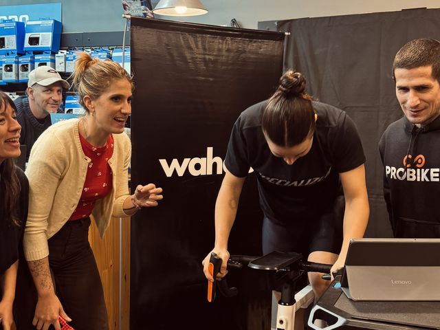 Una ciclista pedaleando en un rodillo Wahoo en la Wahoo Night, con la gente alentando al lado